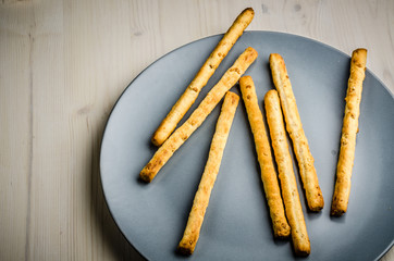 rustic breadsticks in a dish on wood table, close up, background