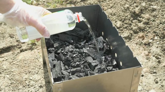 Hand Pouring Lighter Fluid Coals In The Brazier