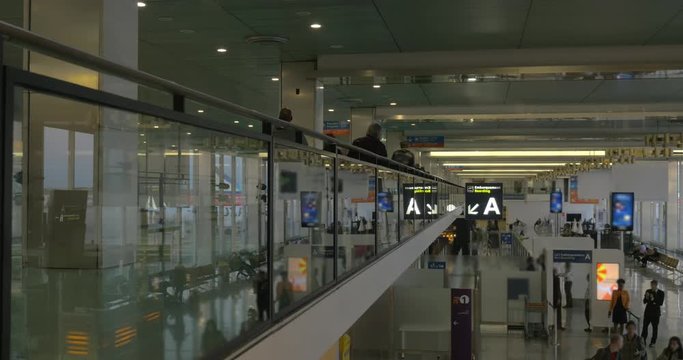 People traffic on the ground and first floors of modern airport hall with passengers shot from back