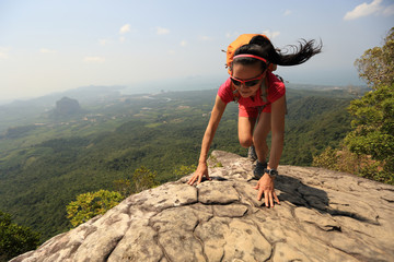 young asian woman hiker climbing rock on mountain peak cliff