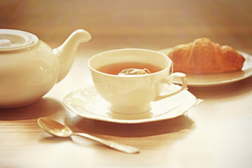 Cup of tea with croissants on table