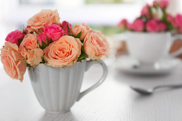 Bouquet of beautiful roses in a cup on a  table