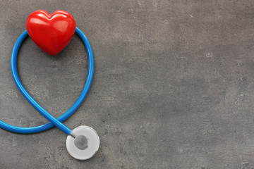 Stethoscope with red heart on grey background