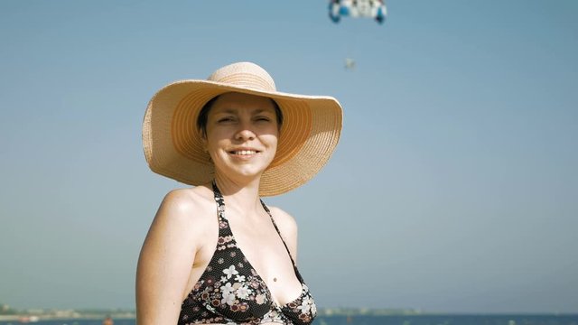 A woman is standing on the beach with her fancy hat and sunglasses. Fedora hat and sunglasses helps to prevent direct contact of eye and the sun.