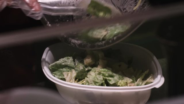 Serving caesar salad into a client's bowl in a restaurant