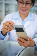 Smiling pharmacist accepting payment for the medicine