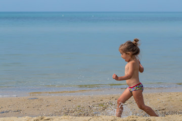 Fototapeta na wymiar little girl running on the beach, joyful emotions,