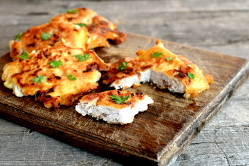 Turkey meat pieces fried in batter and garnished with parsley leaves. Cut roasted Turkey cutlets on a cutting board and an old wooden background. Cooking poultry product