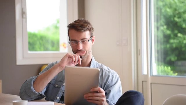 man at home working on digital tablet