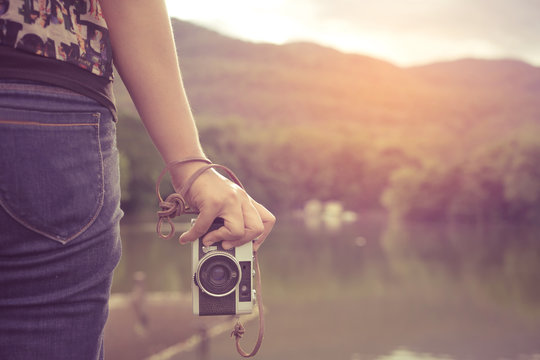 Close-up shot of woman hand holding retro camera. young hipster girl photographer with film camera - vintage filter color effect style.