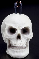 uomini d'affari in miniatura stringono accordo su teschio
