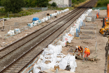 ILKESTON, ENGLAND - AUGUST 1: Construction workers on site next to a section of railway track. In Ilkeston, Derbyshire, England. On 1st August 2016. - obrazy, fototapety, plakaty