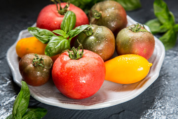 Colorful tomatoes of different sizes and kinds with basil. selec