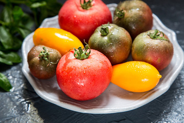 Naklejka na ściany i meble Colorful tomatoes of different sizes and kinds with basil. selec