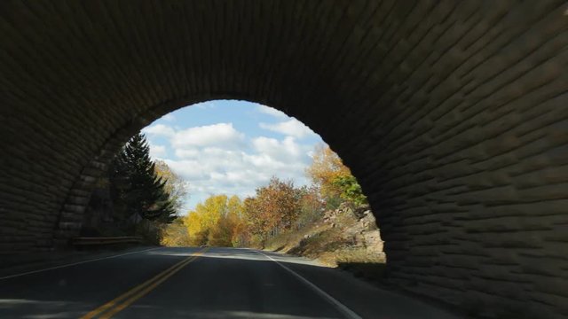 Driving on Eagle Lake Road passing under Acadia All American Road, in Acadia National Park in Autumn.