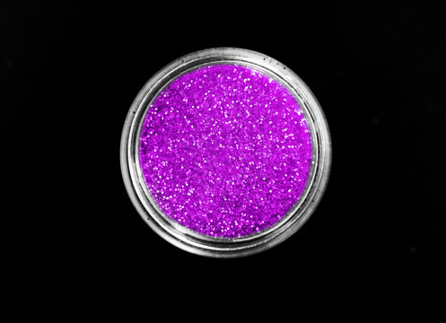 Purple shiny sparkling eye shadow in jar isolated on black background