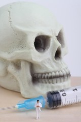 miniatura di medico con siringa e teschio