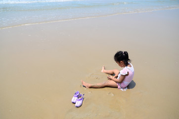 Fototapeta na wymiar Adorable little girl in swimsuit playing at sea beach,Rayong province in Thailand