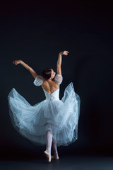 Portrait of the classical ballerina in white dress on black background