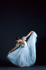 Portrait of the classical ballerina in white dress on black background