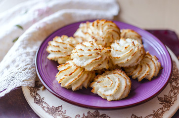 Violet plate of coconut cookies on wooden background. Close up s
