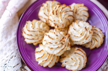 Violet plate of coconut cookies on wooden background. Close up s