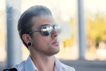 Young man smoking electronic cigarette outdoors