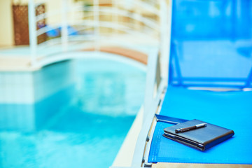 the tablet PC and phone on the deck chair near the pool - freelance or remote work concept