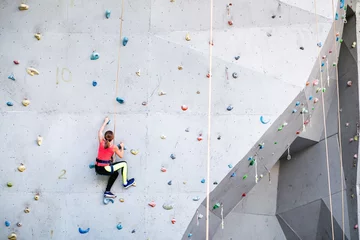 Rolgordijnen active young woman on rock wall in sport center © EdNurg