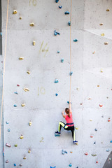 active young woman on rock wall in sport center