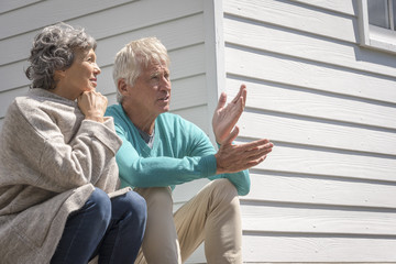Senior couple talking outside of house