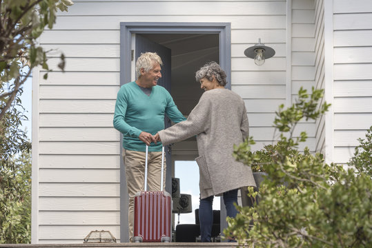 Senior man welcoming woman at doorway