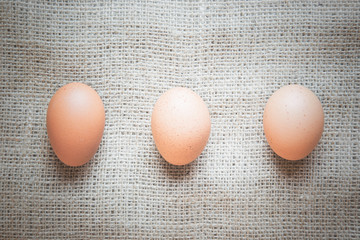 Three chicken eggs on brown burlap