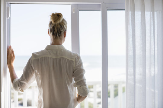 Young woman standing by window at home
