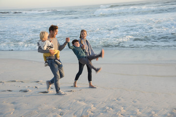 Happy young family having fun on the beach at sunset