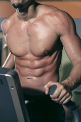 Young man exercising in the gym on the elipsoid stepper