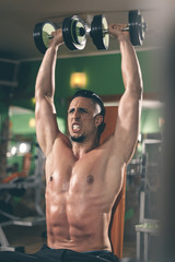 Fototapeta na wymiar Muscular guy lifting weights in the gym 