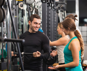 Fototapeta na wymiar Active people having weightlifting training in club