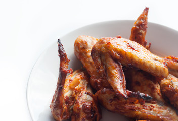 Grilled spicy chicken wings in white dish. Chicken wings isolated on white background.