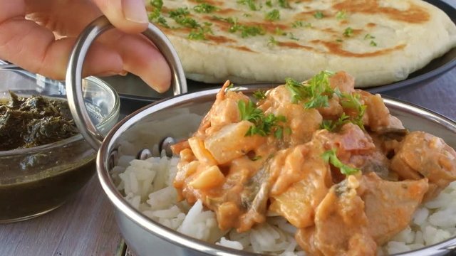 Indian woman serve a traditional Indian butter chicken curry with basmati rice. Food background. 4K