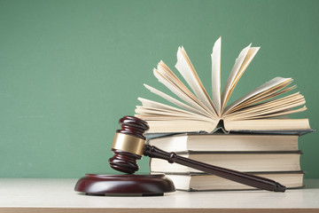 Law concept - Book with wooden judges gavel on table in a courtroom or enforcement office.