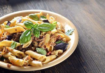 pasta with meat and basil on a plate on a wooden background