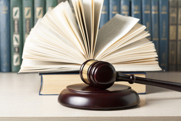 Law concept - Book with wooden judges gavel on table in a courtroom or enforcement office.