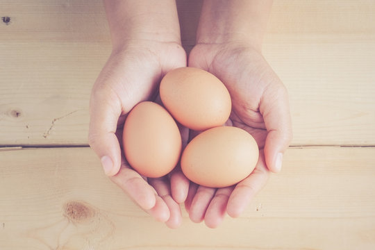 hand holding egg on wooden background with filter effect retro v