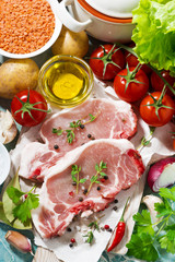 two pieces of pork on a cutting board and fresh ingredients, ver