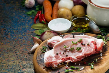 two pieces of raw pork on wooden cutting board and ingredients