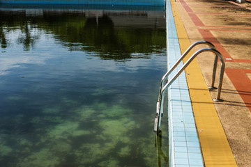 Old abandoned swimming pool with dirty water