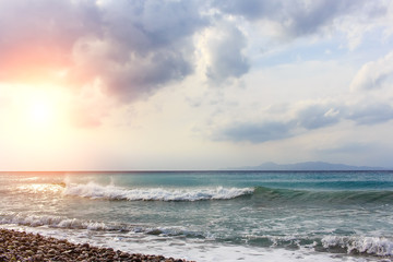 Fototapeta na wymiar pebble beach and sun with cloudscape
