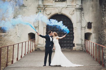 The bride and groom with smoke bombs on the background of castle