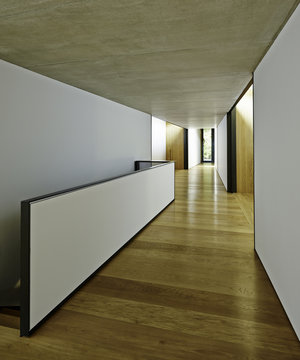 View of contemporary, minimally decorated, hallway with black and white wall and half wall around staircase.